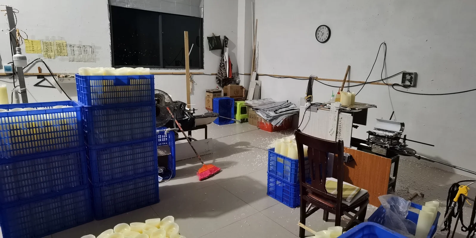 Factory room with blue crates, candle components and worktables used for assembling LED candle products