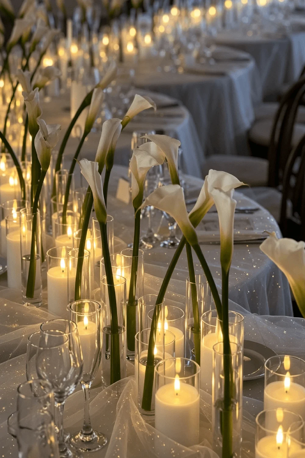 Clear glass candle holders with warm LED candles arranged among white flowers on a decorated wedding table