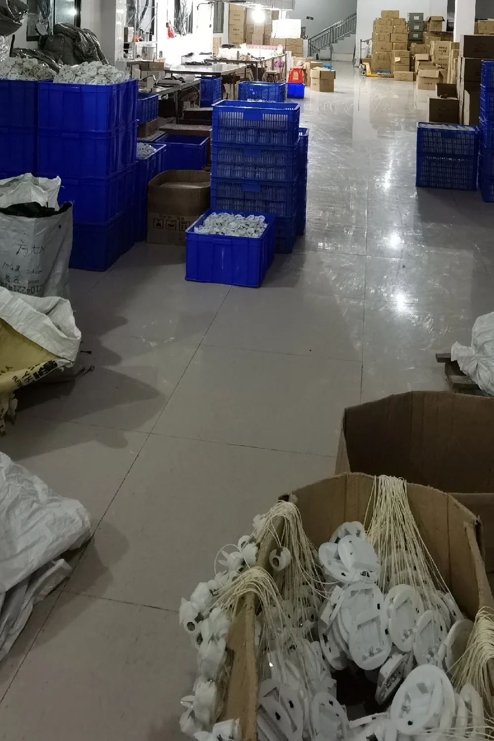Blue production crates and boxes holding LED tea light components in a bright factory workspace